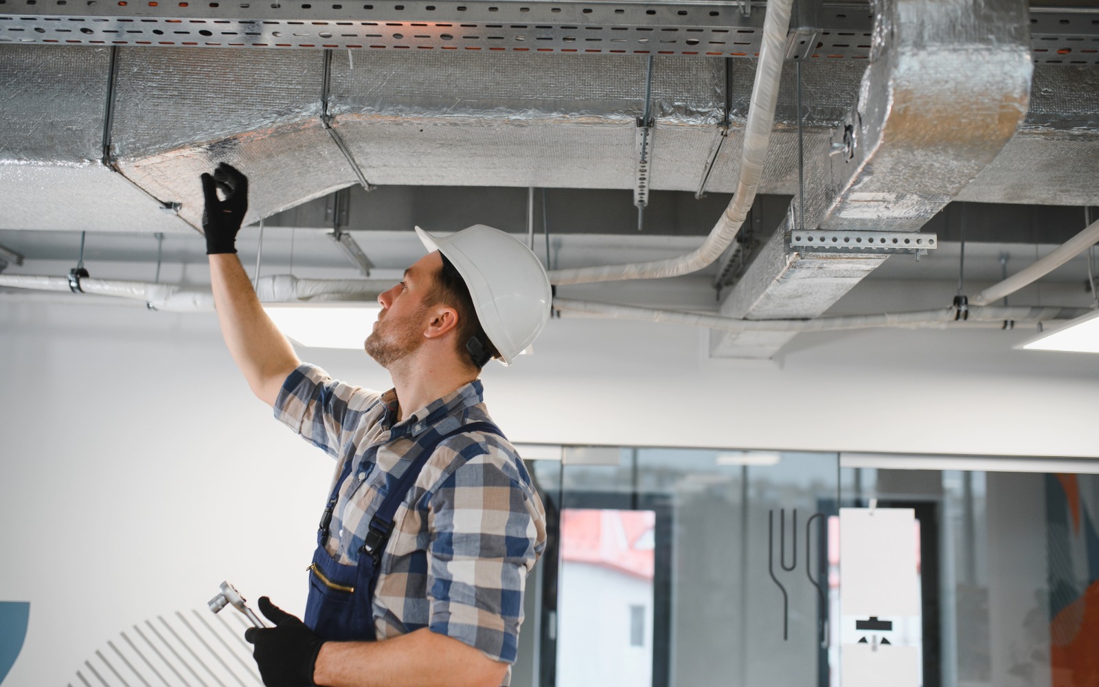 Facility maintenance technician working on ductwork